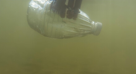 Plastic bottle floating under water with a hand reaching to retrieve it