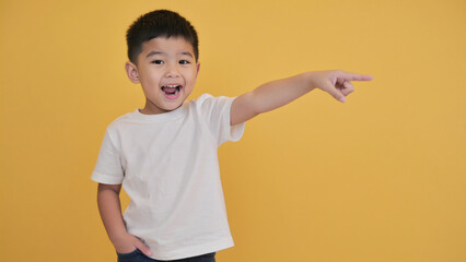 A young boy is pointing at something with his finger, curious and engaged