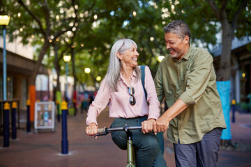 Mature multiethnic couple having fun during a stroll with bike