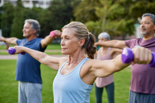 Senior active woman doing dumbbell exercises with friends