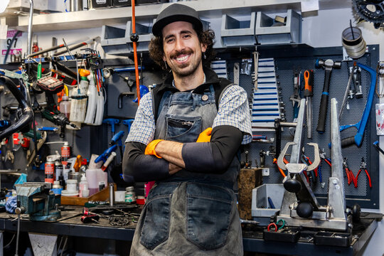 Bicycle mechanic smiling with crossed arms in workshop