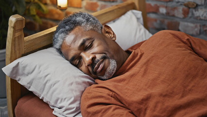 A person lying down in a bedroom, eyes closed, resting