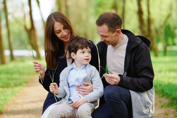 family outdoor bonding moment featuring mother, father, and young son enjoying nature walk in...