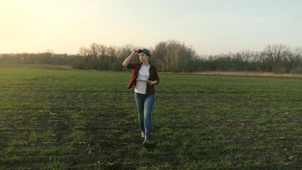 A woman agronomist walks across the field and works online in a tablet, a farmer makes an analysis...