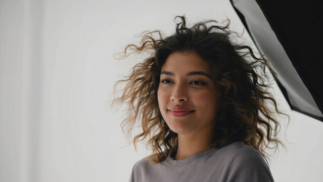 A woman with curly hair holds an umbrella, ready for unexpected weather