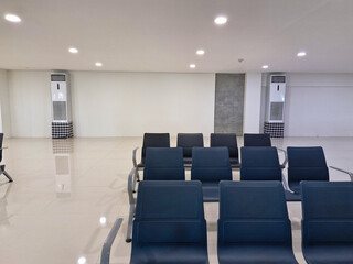 Empty airport waiting lounge with neatly arranged blue chairs, offering a peaceful and clean atmosphere.