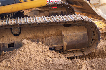 Large piece of machinery with a yellow and black color scheme is sitting in the sand. The machine...