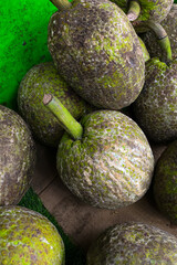 Close-up of fresh breadfruits with rough, green-brown textured skin displayed at a traditional market, stacked together for sale in a natural setting.