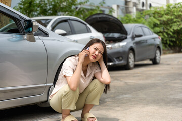 Asian woman using phone calling car mechanic to fix broken car on road
