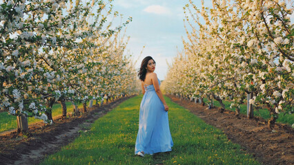 A woman wearing a blue dress stands amidst a lush green forest, perfect for editorial or commercial use