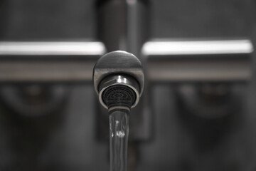 Clean water flowing from a brushed metal faucet aerator in a contemporary bathroom, creating an atmosphere of hygiene and refreshment while enhancing modern interior design