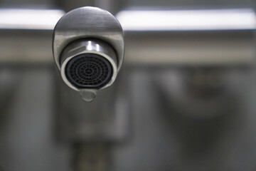 Dripping water from a modern faucet in a bathroom highlights the issue of water waste and emphasizes the crucial need for conserving valuable water resources indoors