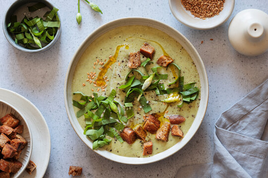 Bowl of wild garlic soup with croutons and herbs in a studio setting
