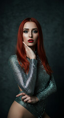 Stunning portrait of a model in a sleek, high‑contrast studio setting, wearing a shimmering metallic silver knit halter top paired with glossy, sculptural sleeves and high-waist bottoms.