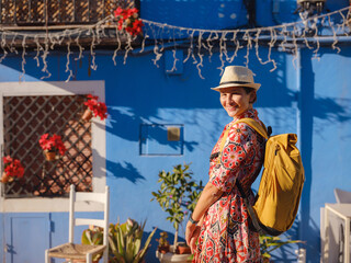 Woman in dress strolls through colorful streets of coastal town of La Vila Joiosa or Villajoyosa....