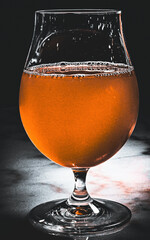 A stylish glass containing a vibrant orange beverage set against a contrasting dark backdrop,...
