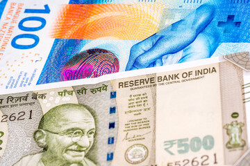 100 Swiss frank and 500 Indian rupee pound banknotes. International trade concept