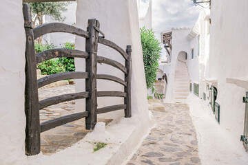 Traditional Wooden Gate and Whitewashed Architecture in Binibeca Vell. Menorcan Coastal Alley, Cobblestone Street, Mediterranean Village Charm