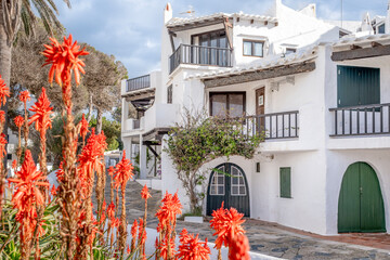 Striking Red Flowers Against Whitewashed Architecture in Binibeca Vell. Menorcan Coastal Village, Traditional Buildings, Arched Doors, ideal for travel and architectural marketing
