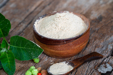 Withania somnifera (Ashwagandha) dried root Powder, green leaves Medicinal Herb. Ashwagandha on wooden background