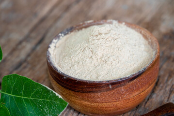 Withania somnifera (Ashwagandha) dried root Powder, green leaves Medicinal Herb. Ashwagandha on wooden background