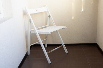 White chair stands in corner on veranda or balcony