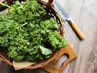 Fresh green curly kale leaves on a wooden table. Selective focus. Rustic style. Healthy vegetarian food 