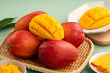 Fresh ripe mango with cubes on green table background.