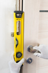 Checking the correct installation of an interior door, by a craftsman using a level, close-up