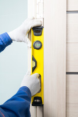 a professional craftsman checks the correct installation of the doorway using a yellow level