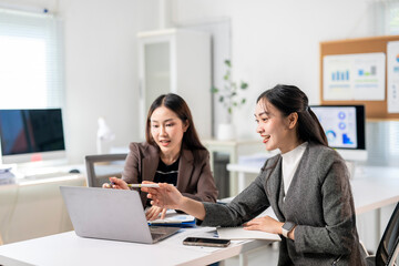 Two businesswomen discussing using laptop in modern office