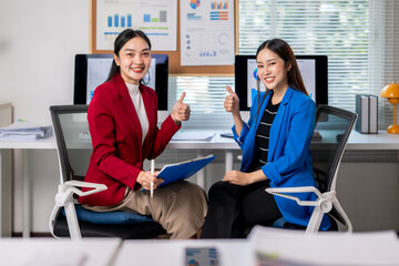 Two businesswomen showing thumbs up in modern office