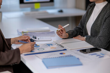 Businesswomen working together analyzing financial charts and business data
