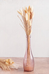 Elegant natural bouquet of dried yellow different autumn plants and flowers in pink purple glass...