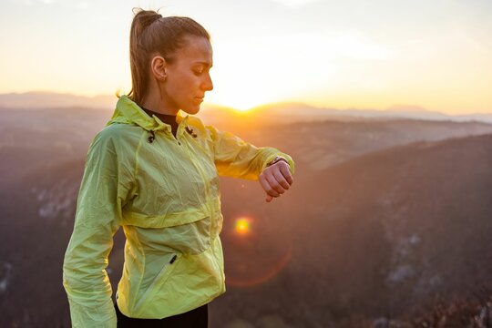 Woman checking smartwatch during sunrise hike