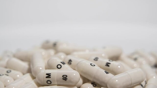 Pile of Capsules in Rotation. The camera captures a turning mound of identical white capsules with black text. The rotating motion highlights the uniformity and medical labeling.