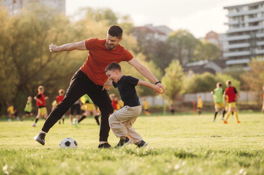 Learning how to play soccer. Father and son are having fun outdoors - Powered by Adobe