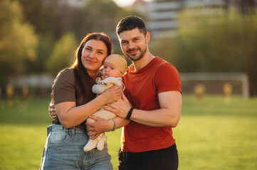Positive facial expression. Happy couple parents are with little baby outdoors
