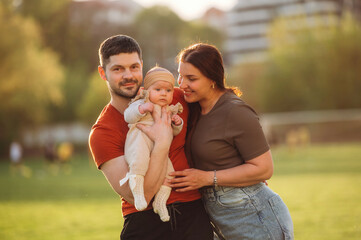 Positive facial expression. Happy couple parents are with little baby outdoors