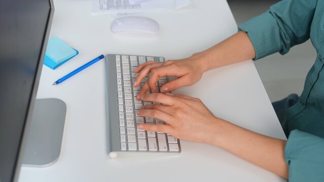 Person Typing on White Keyboard in Office Setting