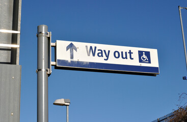 Fototapeta premium Steel Pole with 'Way Out' Sign at Railway Station seen against Blue Sky 