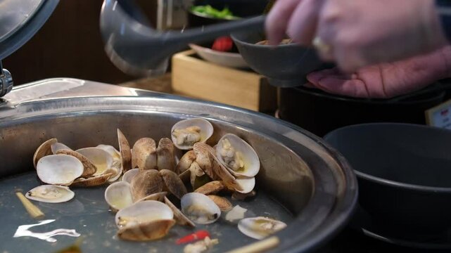 Close Up Cooking Stir Fried Quahaug Shell with Garlic with Ladle and Hot Frying Pan