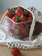 One kilogram of strawberries in a wicker bag on the table. Fresh strawberry harvest