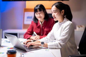 Asian businesswomen working late using laptop in office meeting room