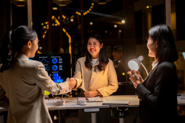 Businesswomen shaking hands over successful deal in modern office at night
