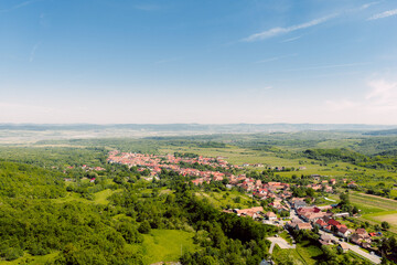 Aerial view of small european village surrounded by green hills and fields