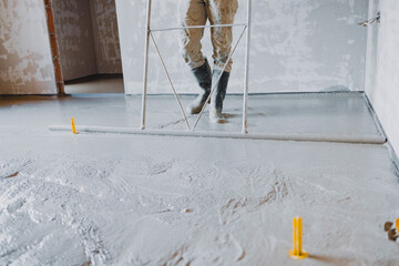 Construction worker leveling concrete surface flooring using a smoothing tool