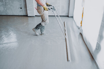 Construction worker leveling concrete surface flooring using a smoothing tool