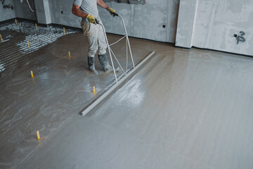Construction worker leveling concrete surface flooring with trowel