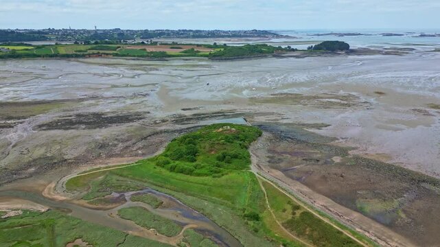 Drone flies forward over sandy Paimpol Bay at low tide, revealing the coastline and distant view of the town - France
